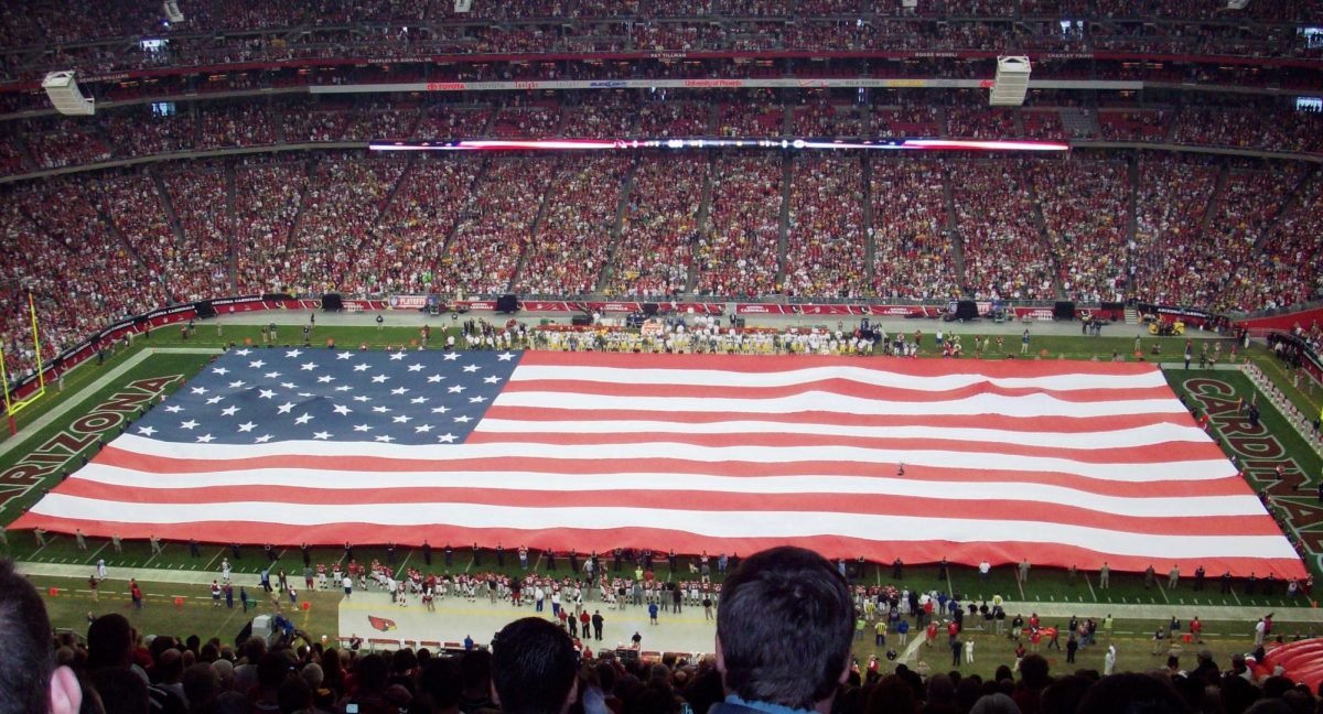 Photo of the American Flag stretched across a football stadium before a game from Creative Commons