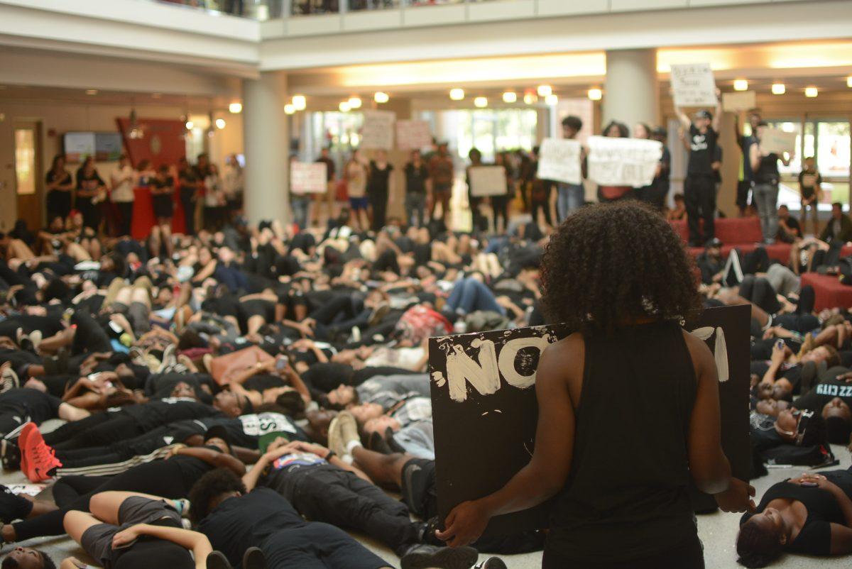 A student holding a sign that reads "disarm the police" stands in the atrium of Talley Student Union as a part of the Blackout on Friday, Sept. 23, 2016. Students and student leaders around campus ogranized the event in response to recent police shootings in Tulsa and Charlotte. The event began in Wolf Plaza where students gathered to show solidarity for the recent police shootings, and ended in the atrium of Talley Student Union.