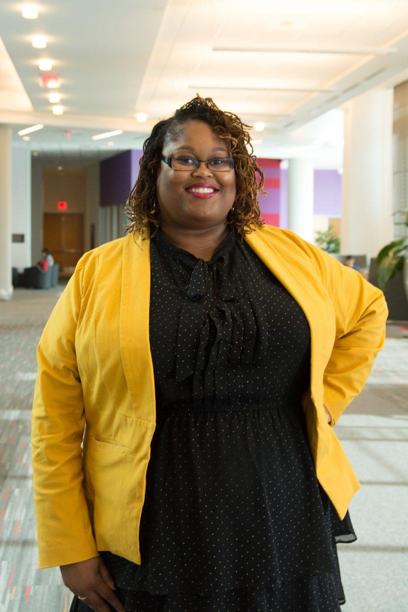 Profile of Angela Gay in black dress with yellow blazer