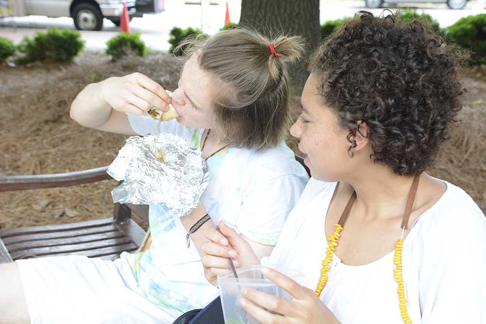 Sam Feldstein/Staff Photographer
Joseph Farley, a sophomore studying psychology and chemical engineering, enjoys an "Atilla the Hen" Pita with his friend Adora Nsonwu, a sophomore studying English" while sitting on a bench in front of the Venture II-A and II-B buildings on Centennial Campus Monday, June 1, 2015.  Farley ordered his pita from the Chick-n-Que food truck.  When asked what brought him out to the food truck, "I was dropping Adora off at work and saw a food truck sign, and I thought it would be nice to get food there" Farley said.