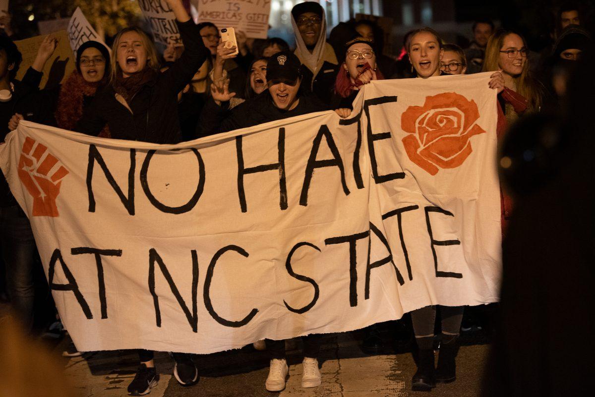 Protesters march together with a banner saying "No Hate at NC State."