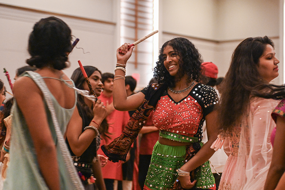 Teju Lankipalli, a graduate student studying textiles, dances with a dandiya stick during Triangle Garba at the Talley Student Union Ballroom on Friday, Oct. 25, 2024. Dandiya Raas is a folk dance that involves dancing with one or two sticks.