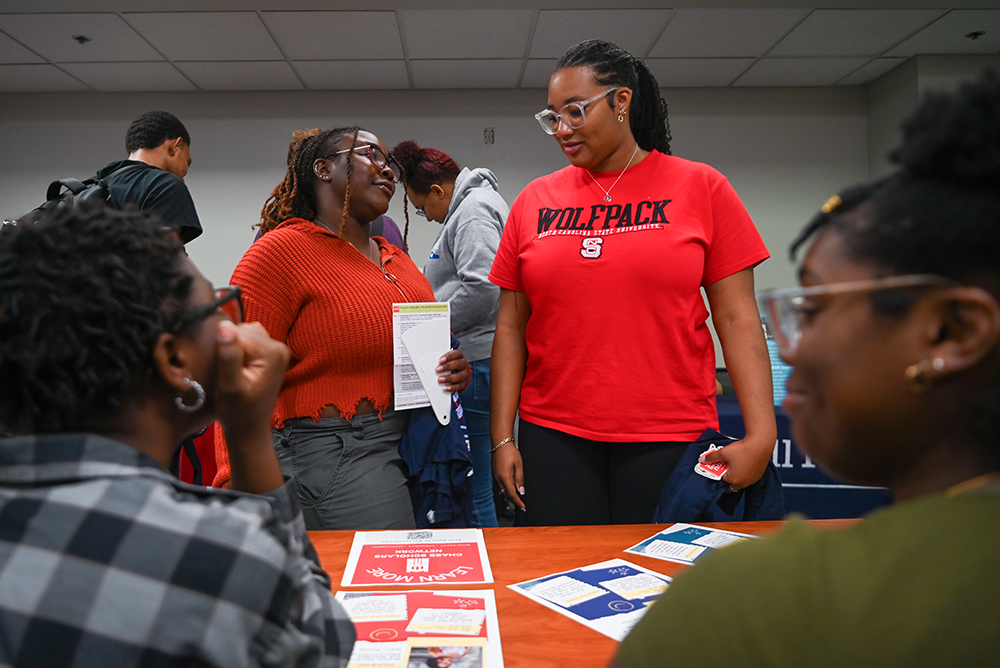 Syndey Gandy, a second-year studying nutrition, and Naomi Gardner, a second-year studying microbiology, talk with the table for the CHASS Scholars Program during Harambee at Witherspoon Student Center on Friday, Sept. 27, 2024. Harambee is held by the African American Cultural Center to link student on campus resources.