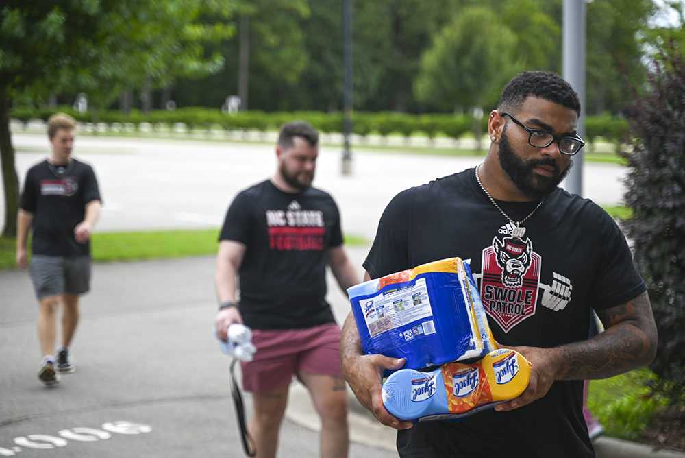 Davin Vann, a graduate student and defensive captain of the NC State football team, carries donated goods during NC State's Football Hurricane Relief Drive at Close-King Indoor Practice Facility on Tuesday, Oct. 1, 2024. The drive was led by defensive captain Vann. Community members were able to donate water, hygeine products,  canned food and blankets from Sept. 30 to Oct. 2.