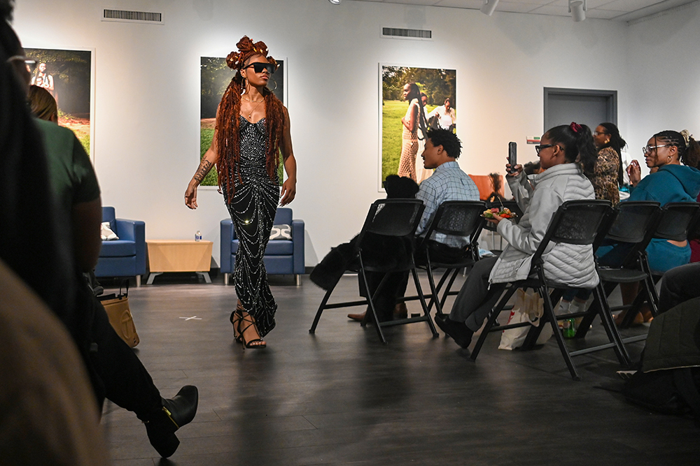 Zania Sanders, a fourth-year studying science, technology and society, struts through a crowd of attendees during the opening of the "Crowning Glory" exhibition in the African American Cultural Center Art Gallery and Library on Thursday, Feb. 6, 2025. The exhibit opening featured food, music, poetry and hair modeling.