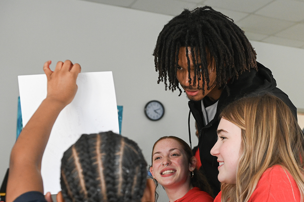 Mary Ledford, a second-year studying middle grades education, Paul Evans-Robinson, a first-year in exploratory studies, and Caroline Blount, a second-year studying psychology, look at a student's craft during the SAY x BMI: Empowering Black Youth Voices event at RISE Charter School on Thursday, March 6, 2025. The Black Male Initiative and Students Advocating for Youth Living and Learning Villages led RISE students in after-school activities with crafts and games.